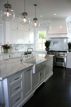 a large kitchen with white cabinets and marble counter tops, along with an island in the middle