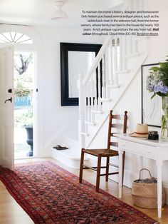 a room with a rug, chair and mirror on the wall next to a staircase