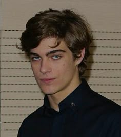 a young man in a black shirt is looking at the camera and has blue eyes