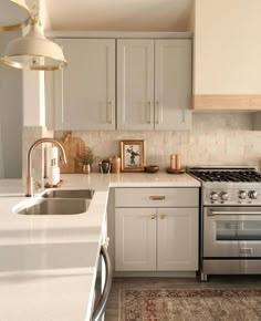 a kitchen with an oven, sink, and stove top on a rug in front of the counter