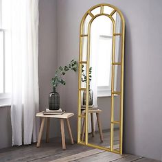 a large gold framed mirror sitting on top of a wooden floor next to a table