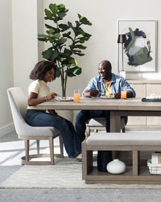 a man and woman sitting at a table with orange juice in front of their faces