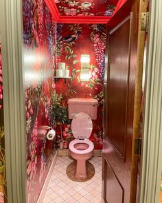 a pink toilet sitting in the middle of a bathroom next to a red tiled floor