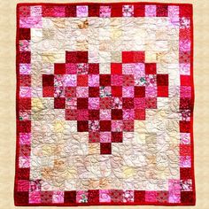 a red and white quilt with pink squares on the front, along with an orange border