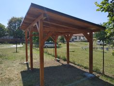 a wooden pergola sitting on top of a grass covered field next to a fence