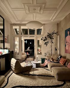 a living room filled with furniture and a painting on the wall above it's windows