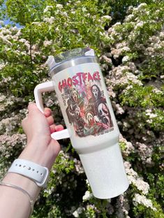 someone holding up a coffee mug with ghostface on it in front of some trees