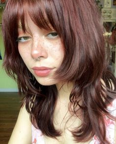 a woman with freckled hair and piercings on her nose looking at the camera