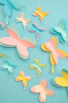 paper butterflies on a blue background with pink, yellow and green ones in the middle