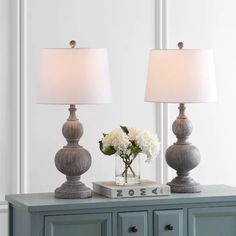 two lamps sitting on top of a blue dresser