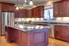 a large kitchen with wooden cabinets and granite counter tops, an island in the middle