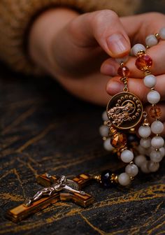 a close up of a person's hands holding rosary beads and a crucifix