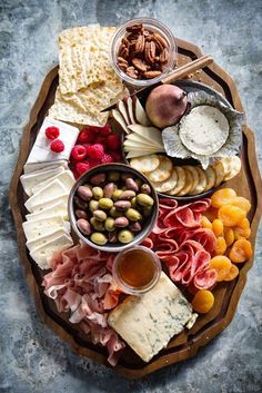 a wooden platter filled with different types of cheese and meats on top of a table