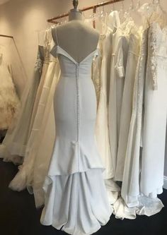 the back of a white wedding dress hanging on a rack in front of other dresses