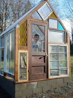 a man standing in front of a small house made out of wood and glass windows