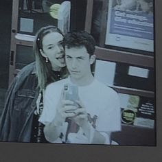 a man and woman standing next to each other in front of a vending machine