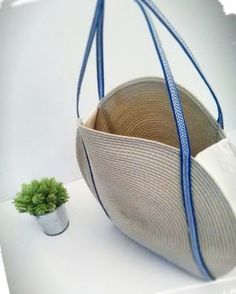 a small potted plant sitting next to an empty purse on a table with blue straps