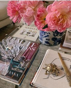 pink flowers are in a blue and white vase on a table next to some books