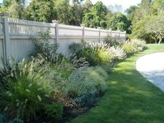 a garden with grass and flowers next to a fence