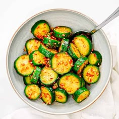 a bowl filled with cooked zucchini on top of a white table