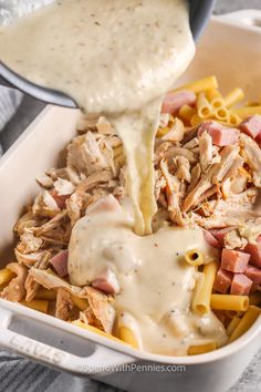 someone is pouring sauce on some pasta in a casserole dish with meat and cheese