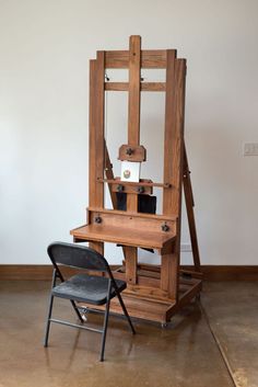 a wooden easel sitting next to a black chair