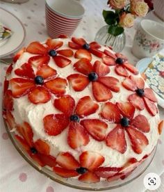 a cake with strawberries and blueberries on it sitting on top of a table