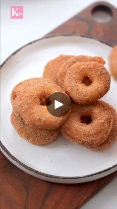 three donuts on a white plate with a wooden board in the background and a video play button