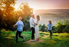 a group of people standing on top of a lush green hillside next to trees and bushes