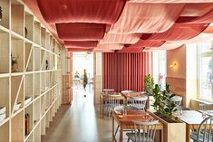 the interior of a restaurant with wooden tables and chairs covered in red cloth coverings