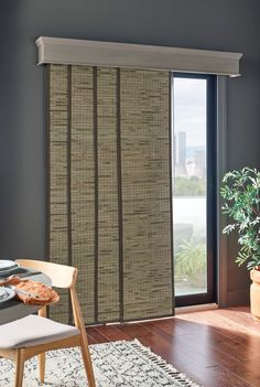 a dining room with a table and chairs next to a sliding glass door that has bamboo blinds on it