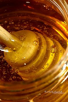 a jar filled with liquid and a wooden spoon in it's top, surrounded by water droplets