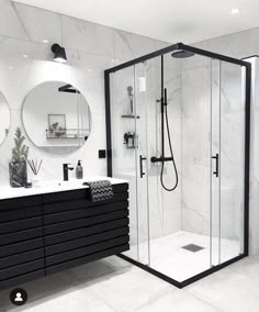 a black and white bathroom with two mirrors on the wall, a sink, and a walk in shower