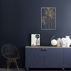 an empty room with blue walls and white vases on the sideboard next to a chair