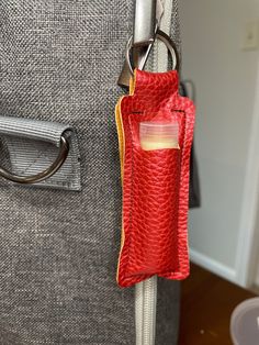 a red bag hanging from the side of a suitcase with a keychain attached to it