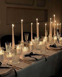 a long table is set with candles and place settings for an elegant dinner or party