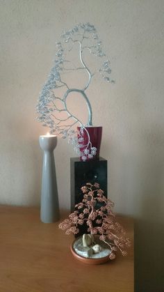 a small bonsai tree sitting on top of a wooden table next to a vase