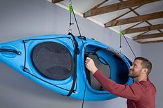 a man holding onto a blue kayak hanging from the ceiling