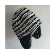 a black and white striped hat hanging on the side of a wall with holes in it