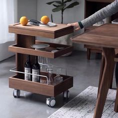 a woman standing in front of a wooden table with wine glasses and bottles on it