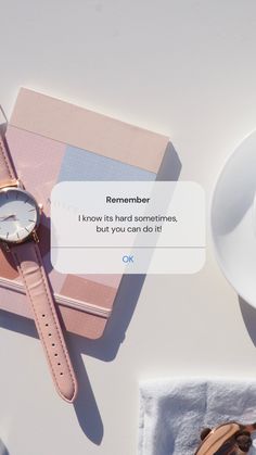 a pink watch sitting on top of a white table next to a cup of coffee