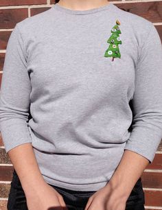 This adorable hand-embroidered t-shirt is perfect to get into the spirit of the season. We carefully hand-embroidered a cute little tree and sewed on some buttons as ornaments. This minimalist design with focus on the tree is a perfect pair for just about any bottom you have in your closet and makes a perfect Christmas gift! Size: Large Note: All of the clothing in our shop is thrifted and serve as a quality base for our hand-sewn/embroidered/felted creations! We, as a shop and as sisters, aim t Holiday Embroidered Tops As Gift, Holiday Cotton Top With Embroidery, Holiday Cotton Embroidered Tops, Festive Embroidered Crew Neck Top, Festive Long Sleeve Cotton T-shirt, Retro Shirt Design, Christmas Tree Shirt, Tree Shirt, Retro Shirts