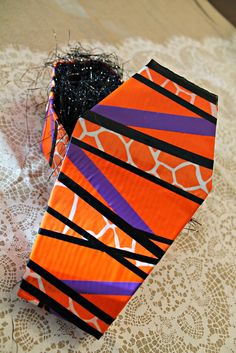 an orange and purple tie sitting on top of a lace tablecloth covered table cloth