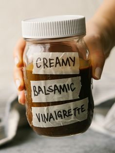 a person holding a jar with some type of food in it that says creamy, balsamc, vinaigrete