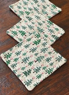 three placemats with christmas trees on them sitting on a wooden table next to each other