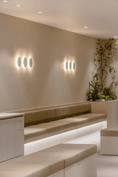 an empty waiting area with benches and lights on the wall above them, along with potted plants