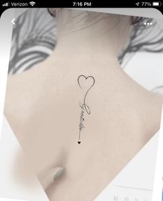 the back of a woman's neck with a heart and arrow tattoo on it