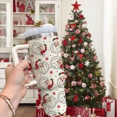 a person holding a coffee cup in front of a christmas tree