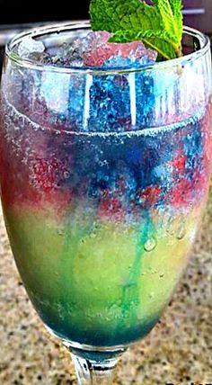 a colorful drink in a glass with a mint sprig on the top and bottom