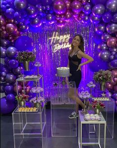 a woman standing in front of a cake and balloons